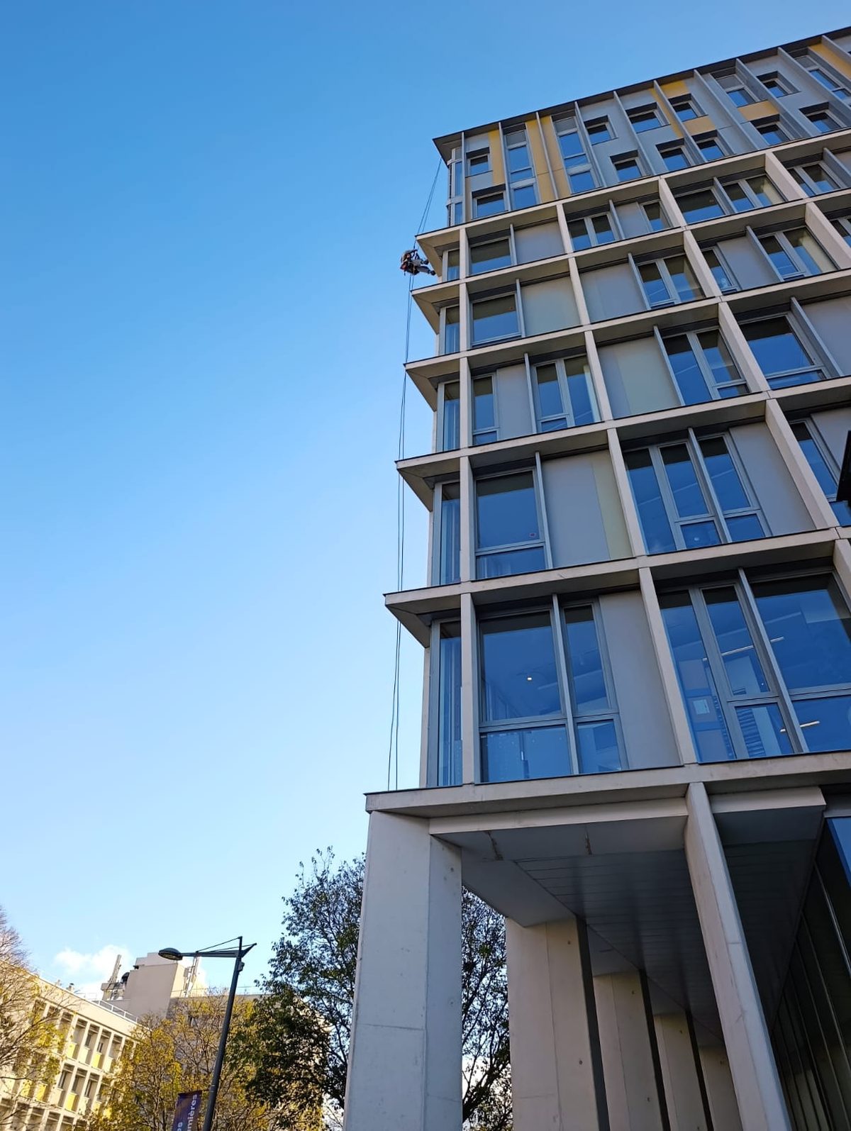 Technicien cordiste descendant le long de la façade d’un immeuble