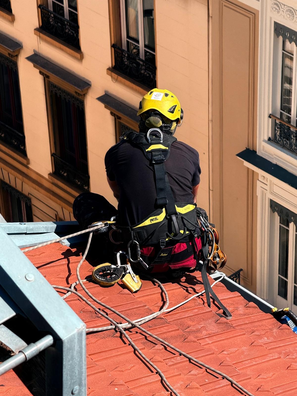 Technicien cordiste équipé intervenant depuis une toiture